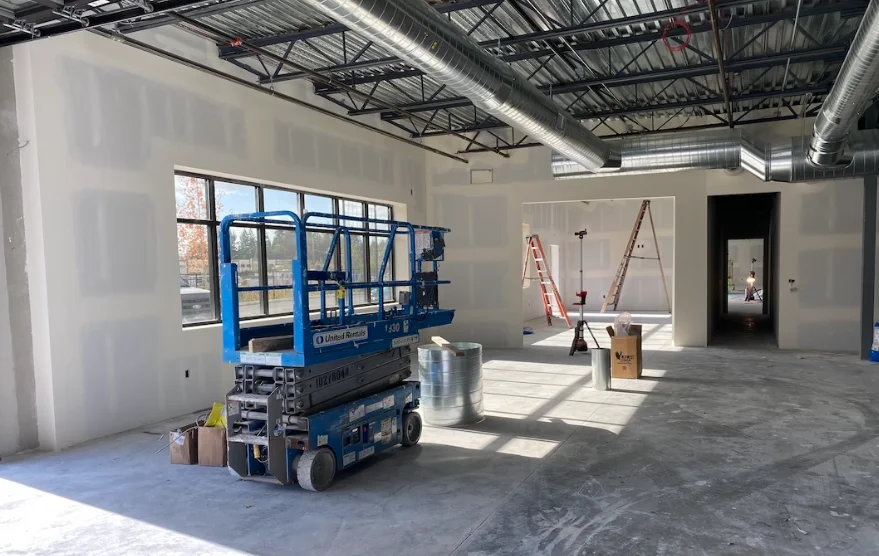 Commercial space with drywall hung under an open steel ceiling and a scissor lift
